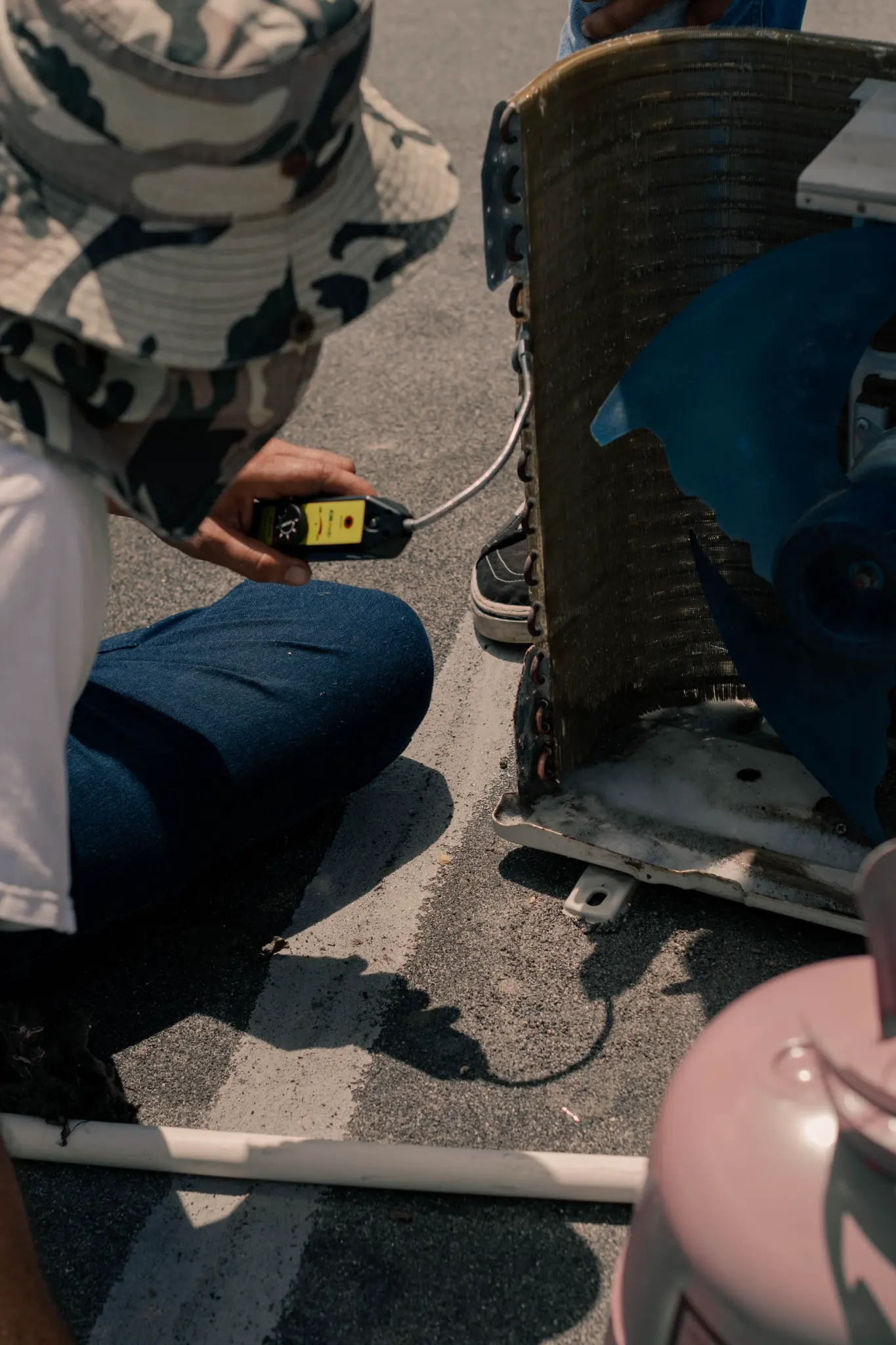 Technician using a handheld detector near an outdoor condenser coil