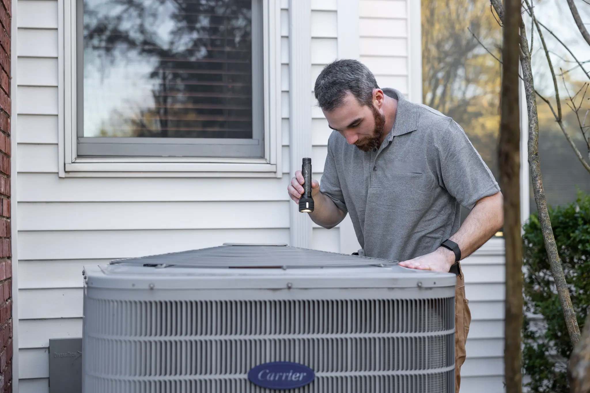 HVAC technician inspecting a residential outdoor air-conditioning unit
