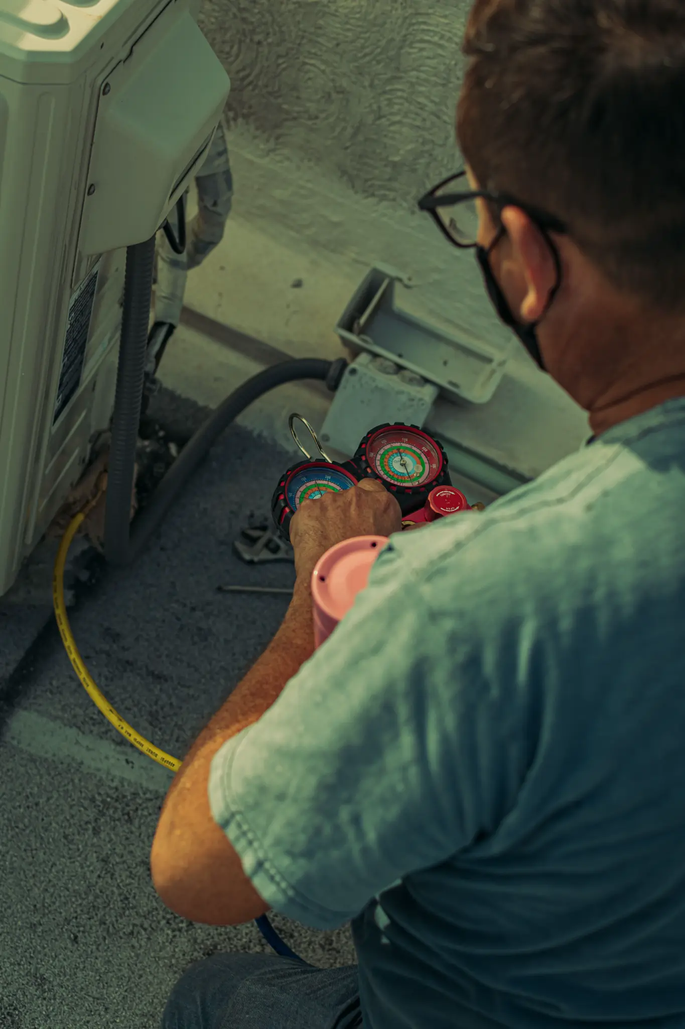 HVAC technician checking refrigerant gauges beside cooling equipment