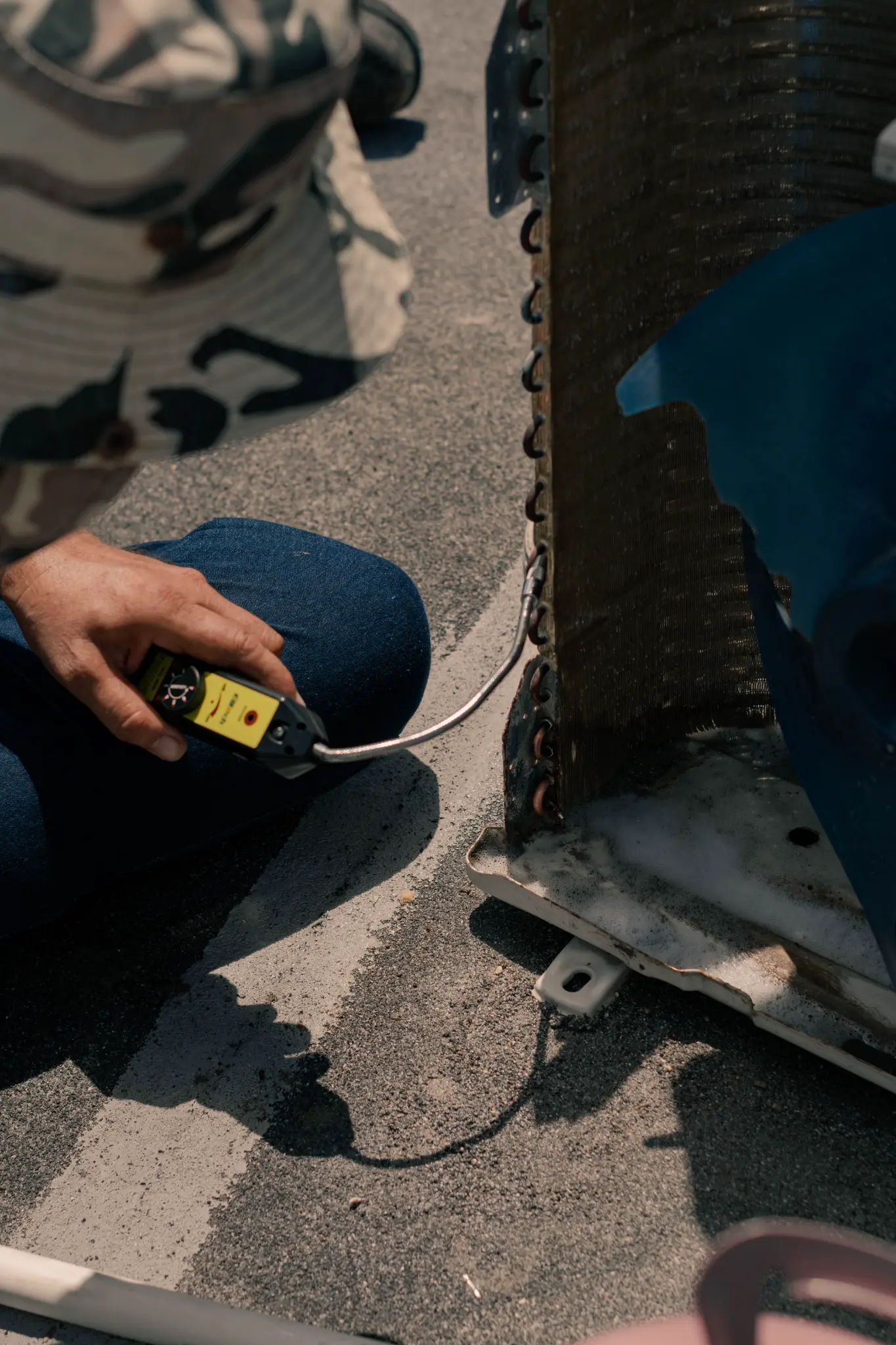 Technician using an electronic testing instrument on an exposed condenser coil