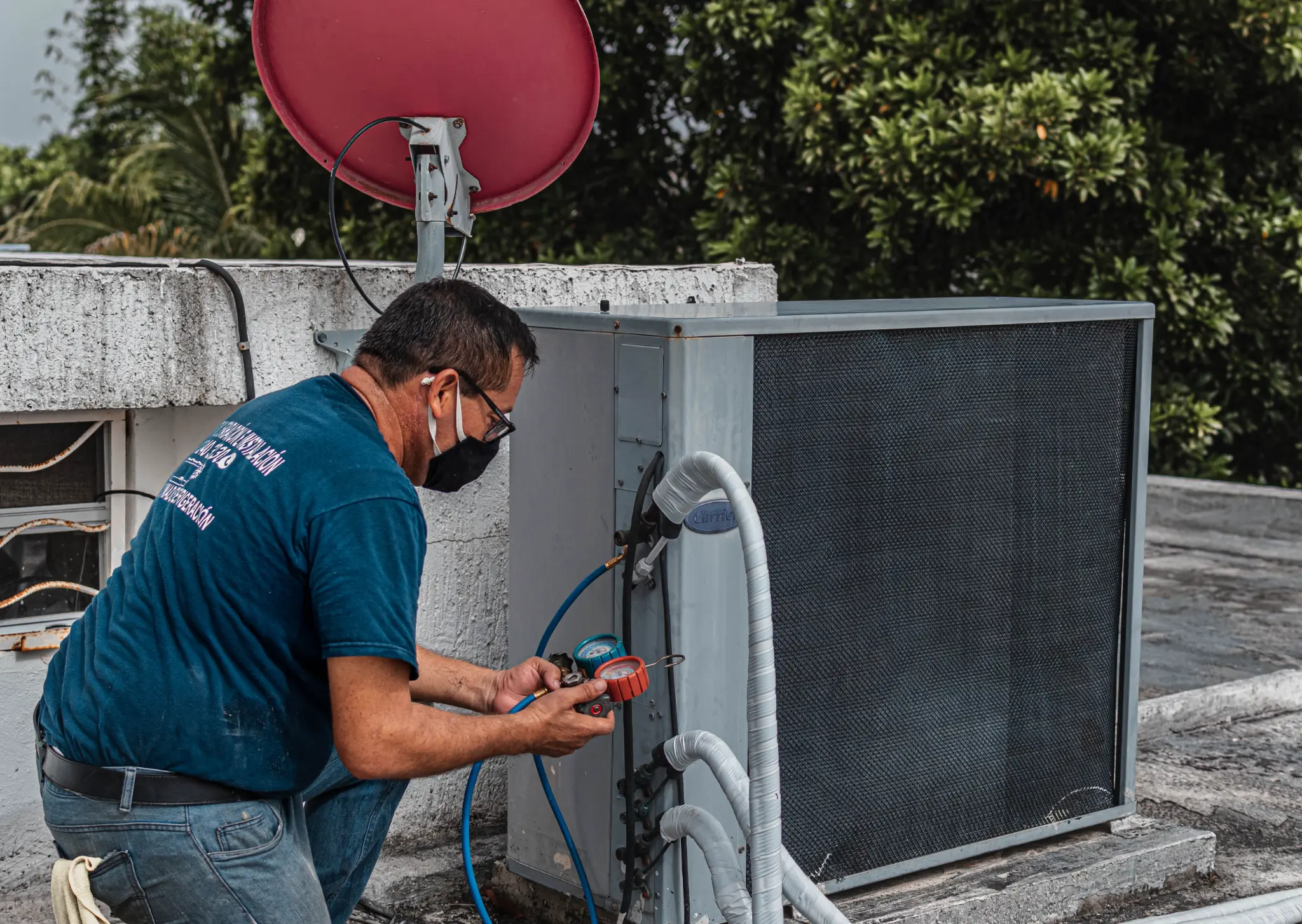 Technician reading pressure gauges on a rooftop air-conditioning unit