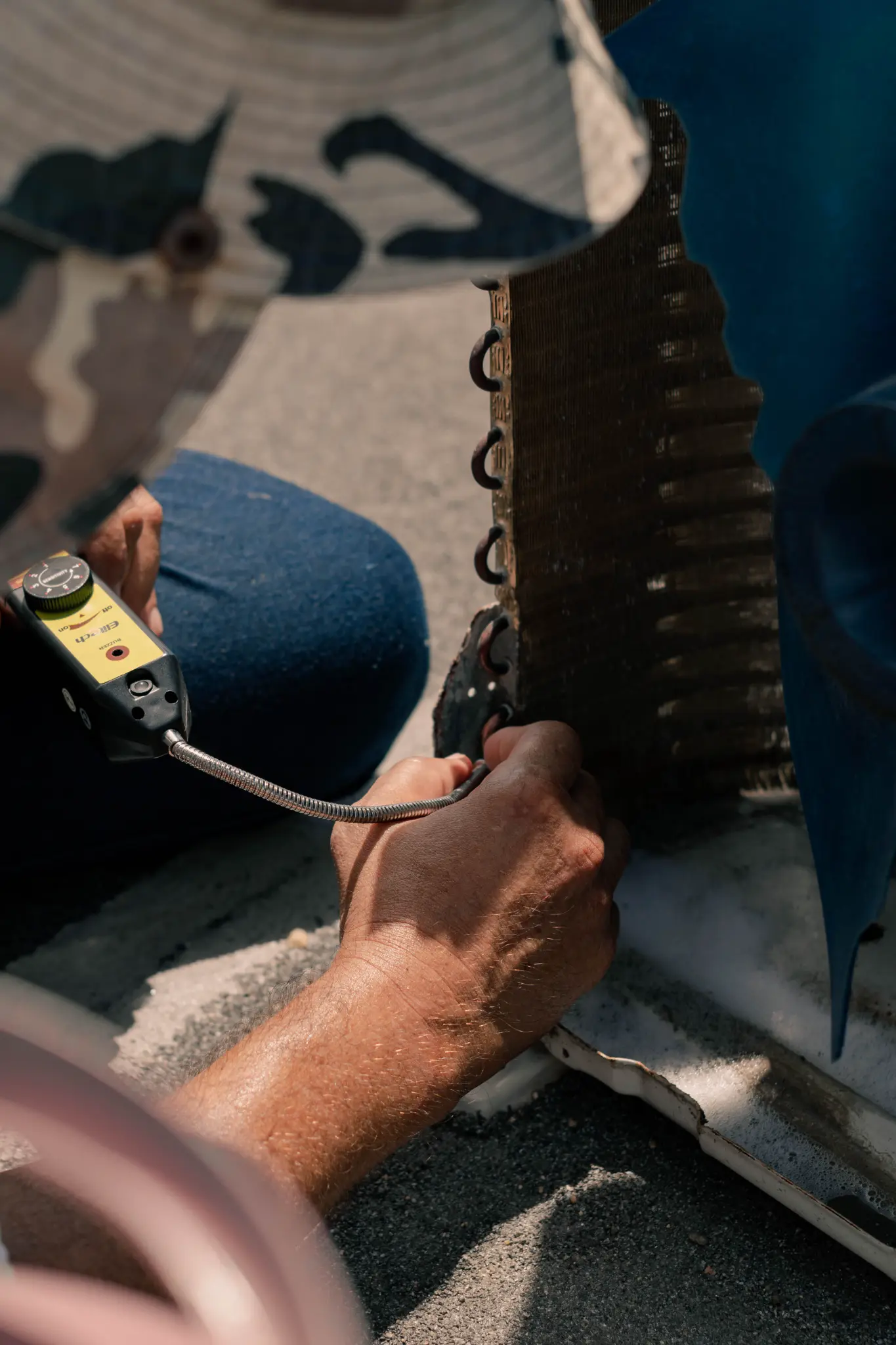 Close-up of a technician testing tubing on an exposed condenser coil