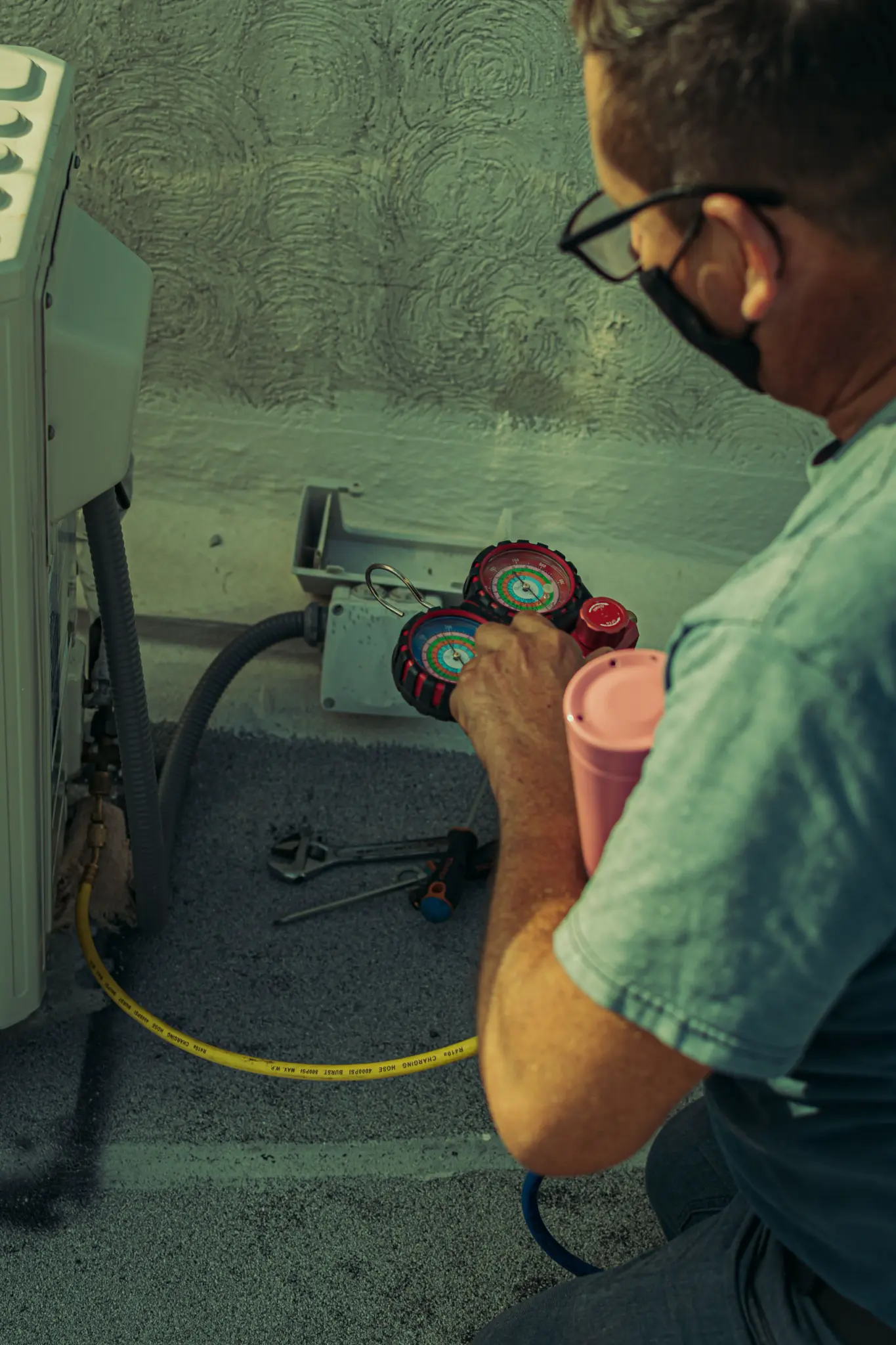 Technician monitoring manifold gauges while servicing HVAC equipment